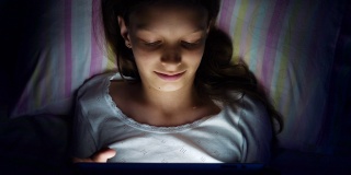 女孩躺在床上用平板电脑看视频