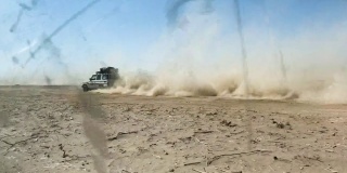 四轮驱动在沙漠上快速行驶，扬起了尘雾