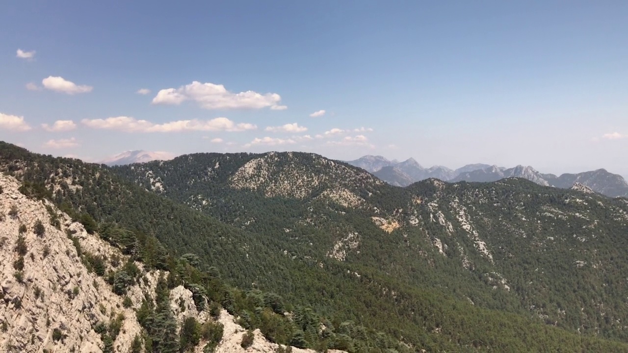俯瞰一个美丽的绿色森林与树木和高岩石山脉。4k高清视频
