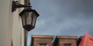 阴天建筑物墙上挂着一盏黑色复古旧灯笼。城市装饰。