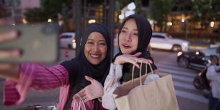 一名年轻的多民族穆斯林女性在繁忙的市中心道路旁愉快地自拍，身后是摩天大楼和城市商店，无塑料袋概念，有快乐记忆的友谊概念