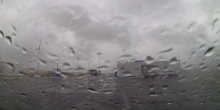 下雨天，从车窗往外看，雨点落在挡风玻璃上，停在加油站附近