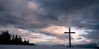 时间从白天流逝到黑夜。在雪地里穿过。冬天的木制宗教十字架。莱斯昴宿星团,瑞士。