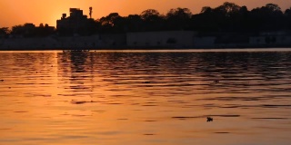 日落时分，平静的河水随着太阳在天空中落下。在印度古吉拉特邦艾哈迈达巴德的萨巴尔马蒂河边。落日湖。