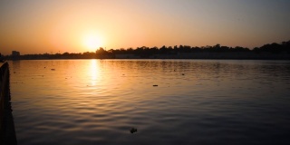印度艾哈迈达巴德，萨巴尔马蒂河滨，夕阳西下，太阳在天空中反射在河水里的美丽景色。日落河景观