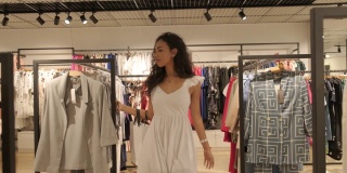 女孩走在时尚的白色礼服服在服装店和时尚精品购物中心