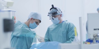 手术切除扁桃体，扁桃体切除术。在现代临床中，在深度麻醉下，使用最新的设备，病人切除腺体，冷等离子法，割喉肿胀，医生工作与新的探针，医用头灯，手术放大镜，两个外科医生