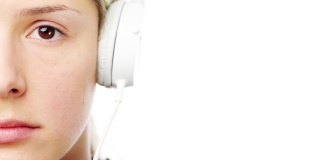 一个年轻女子戴着耳机在白色录音室背景下拍摄的4k视频片段