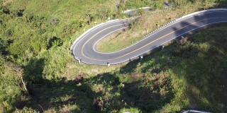 鸟瞰汽车在森林里的乡村道路上行驶。电影无人机拍摄飞行在乡村公路与弯曲的山。