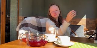 季节性过敏的女孩十几岁，在春天的桌子上擤鼻涕，旁边是致敏茶