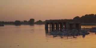 在印度拉贾斯坦邦的斋萨尔梅尔，日落时游客们在湖中央划船的Gadisar湖的景色。