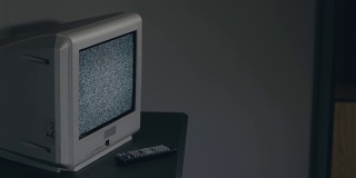 破旧的电视-旧的银色电视在黑房间的黑桌子上