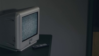 破旧的电视-旧的银色电视在黑房间的黑桌子上视频素材模板下载