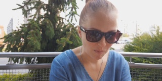 一个戴着太阳镜的漂亮白人女人坐在夏日咖啡馆的桌子旁吃着炸薯条。