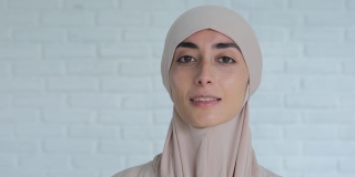微笑的穆斯林妇女的肖像，戴着传统的希贾布头，看着自信的相机。一个阿拉伯女子的外表遵守伊斯兰世界和宗教的法律