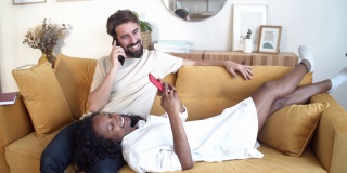 异性恋夫妇躺在公寓沙发上使用智能手机