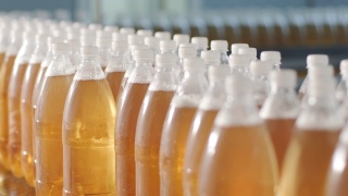 在现代饮料厂，带着瓶装果汁或水的传送带。现代生产的甜苏打水视频素材模板下载