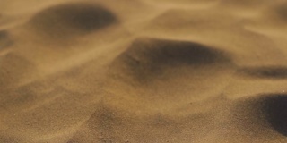 印度拉贾斯坦邦Jaisalmer的塔尔沙漠的山姆沙丘上，沙丘上的沙尘在空中流动的慢动作特写镜头。沙漠中由于风而在空气中流动的沙粒。