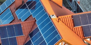 鸟瞰图建筑屋顶与一排排蓝色太阳能光伏板产生清洁的生态电能。零排放的可再生电力