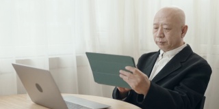 没有头发的亚裔中国高管在开放式办公室里用笔记本电脑打字