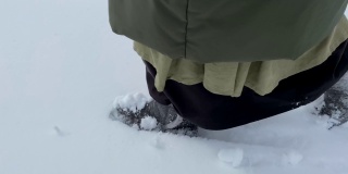 冬天，女人穿着毛毡靴子和长裙走在雪地上，在新鲜的雪地上留下脚印。侧视图。冬季户外活动。新年,圣诞节。脚近距离。4 k
