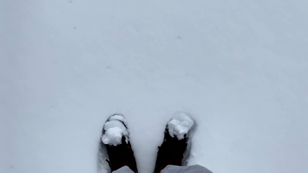 冬天穿登山靴的人走在雪地上，新雪上留下脚印。从眼睛看到的景色。脚近距离。冬季户外活动。新年，圣诞节，4K