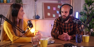 两位主持人戴着耳机在广播中录制播客