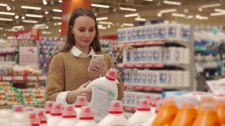 一名女子在超市购物时，用智能手机扫描一瓶洗涤剂上的条形码，查看产品信息和价格视频素材模板下载