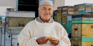 微笑的农民老人的画像，拿着装满蜂蜜的容器，生产有机食品