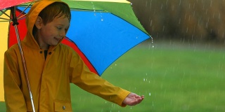 小男孩在雨中打着伞，慢镜头