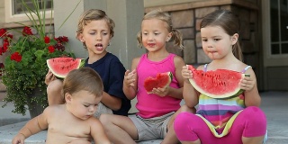 一群孩子坐在门廊上吃西瓜