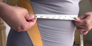 近距离超重妇女测量腰围