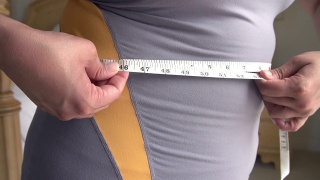 近距离超重妇女测量腰围视频素材模板下载
