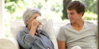 老奶奶坐着看书，孙子拿来了热饮