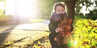 孩子在秋天的公园里扔黄叶。