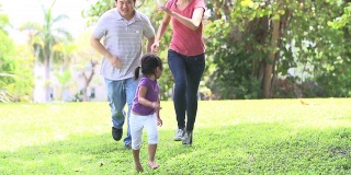 父母和女儿在公园跑步的慢镜头