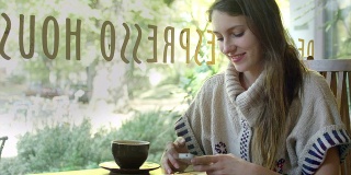 一个年轻女子坐在咖啡馆里，一边喝着咖啡，一边发短信