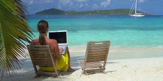 一名女子在加勒比海海滩上用笔记本电脑工作的视频