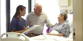 护士在病房里和一对老年夫妇谈话