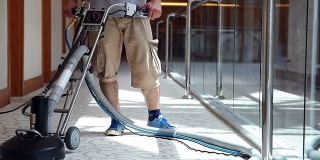 清洁男工人正在清洁酒店走廊的地毯