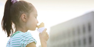 漂亮的小女孩在街上吃冰淇淋
