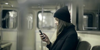十几岁的女孩晚上乘地铁，用智能手机