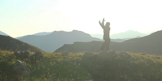剪影中的男子在山上练习武术，锻炼身体
