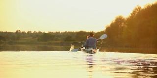 活跃的夫妇在日落皮划艇。健康的生活方式，运动