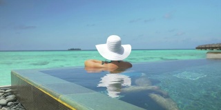 戴着太阳帽的女子在马尔代夫的游泳池里放松