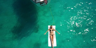 航拍视频性感女人日光浴旁边的帆船