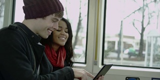 一对情侣在火车上一边看平板电脑一边一起大笑