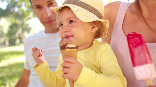 一家人和女儿在公园里愉快地吃冰淇淋