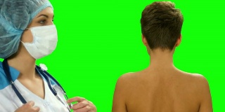 医生用绿色屏幕上的听诊器听一位女病人检查肺部