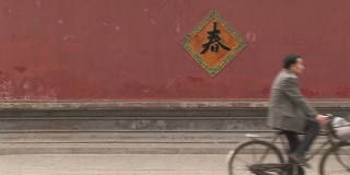 骑自行车经过一堵红墙